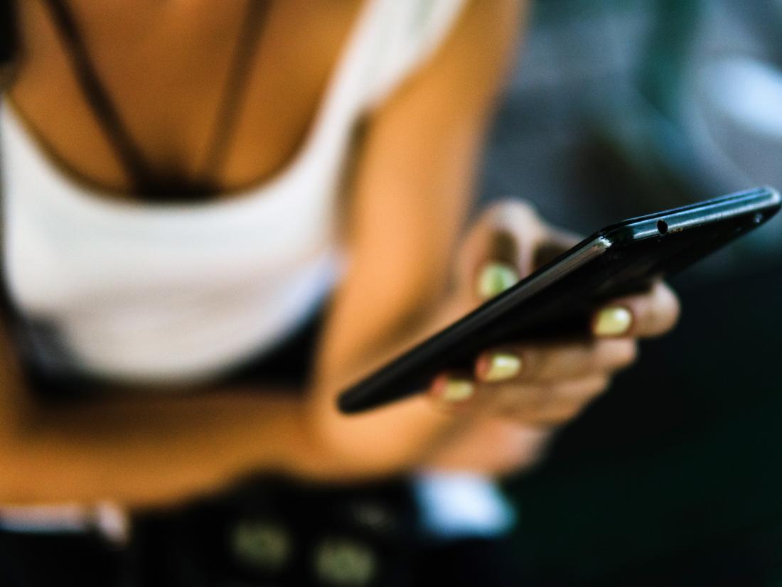 a woman on her phone with yellow nail varnish 