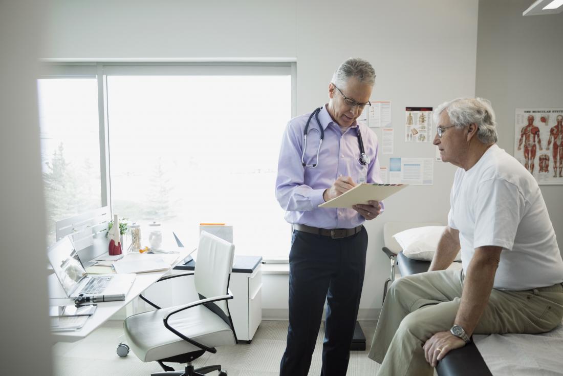 mature male patient sitting on bed in doctor s office while he looks like clipboard