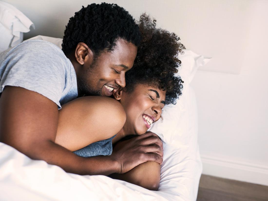a happy couple having a spoon in bed.
