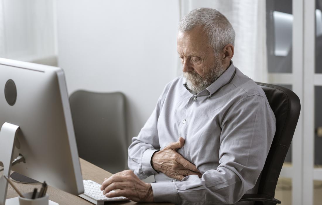 a man sat at a desk and experiencing stomach pain after burping