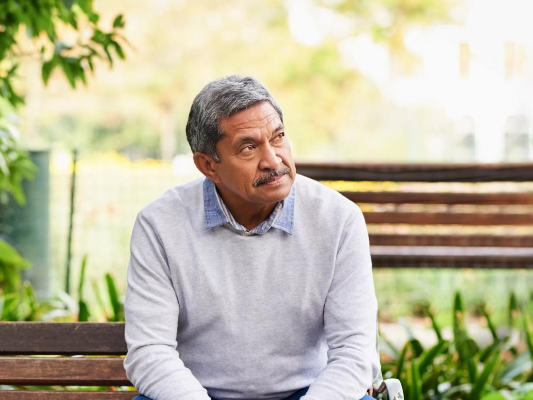 a senior man looking confused whilst sat on park bench possibly due to low levels of acetylcholine in his brain.