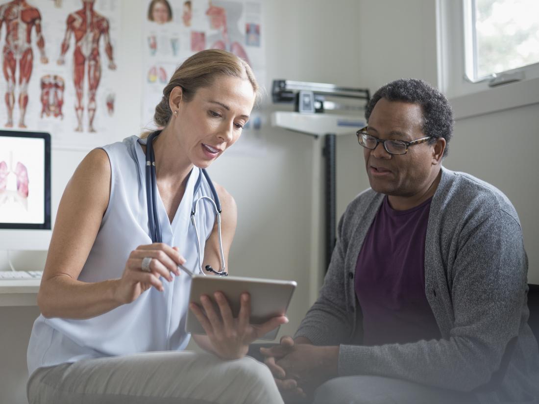 doctor showing patient the appearance of herpes with pictures on tablet device