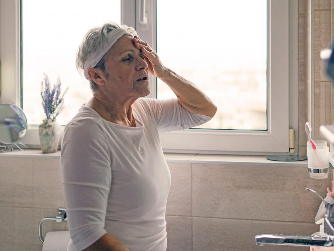 a woman experiencing a headache in bathroom because of hard lumps in her anus. 