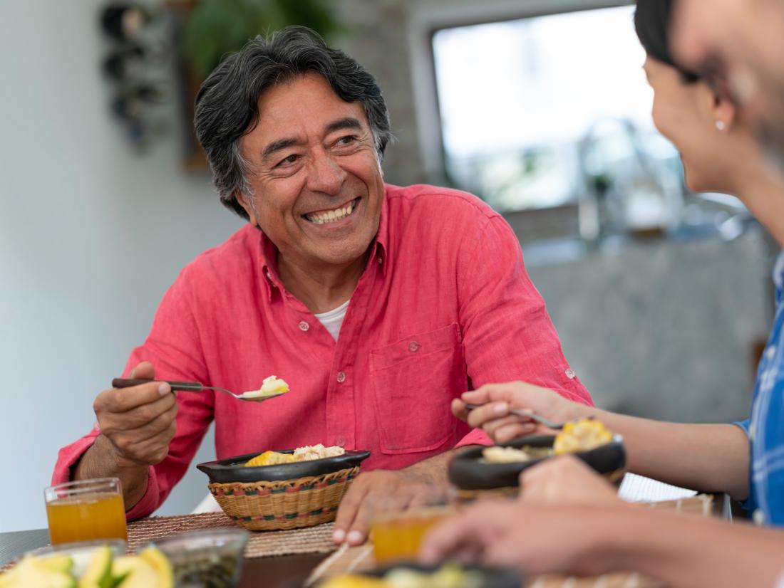 a man looks happy as he eats a meal with others. 