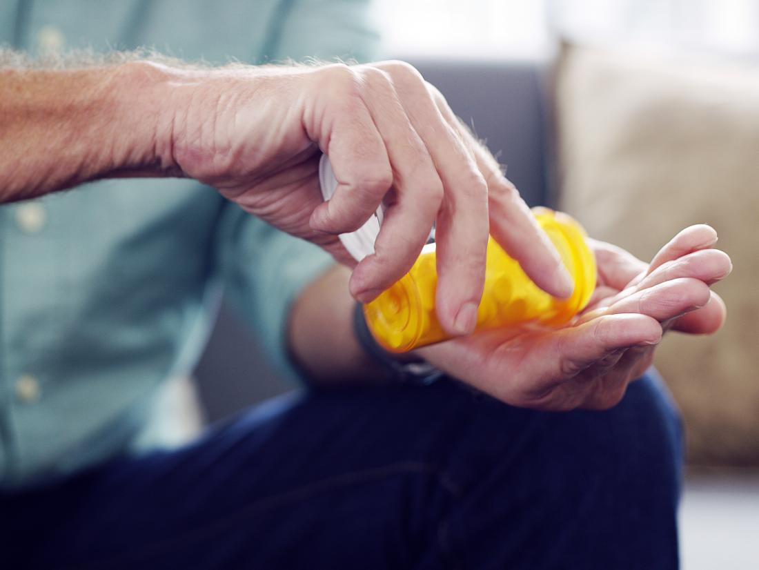 A man pouring Calcium channel blockers from a pill container into his hands. 