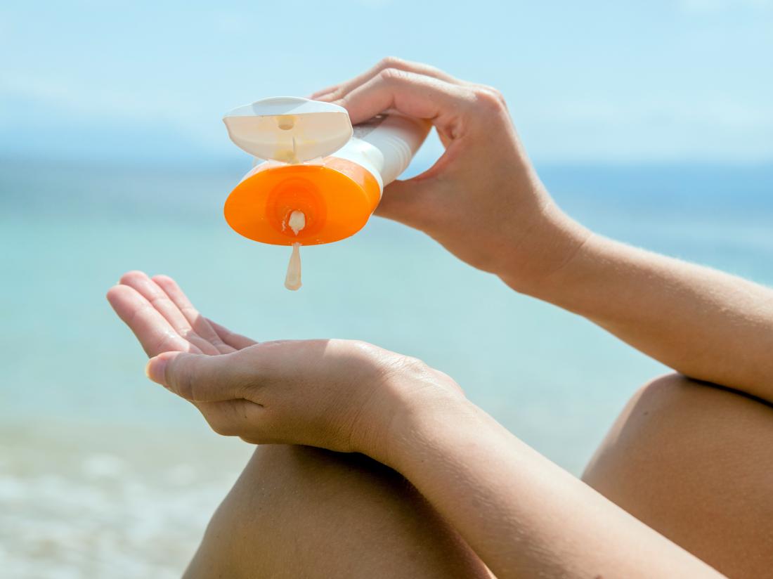 a woman pouring sunscreen from a bottle into her hand. 
