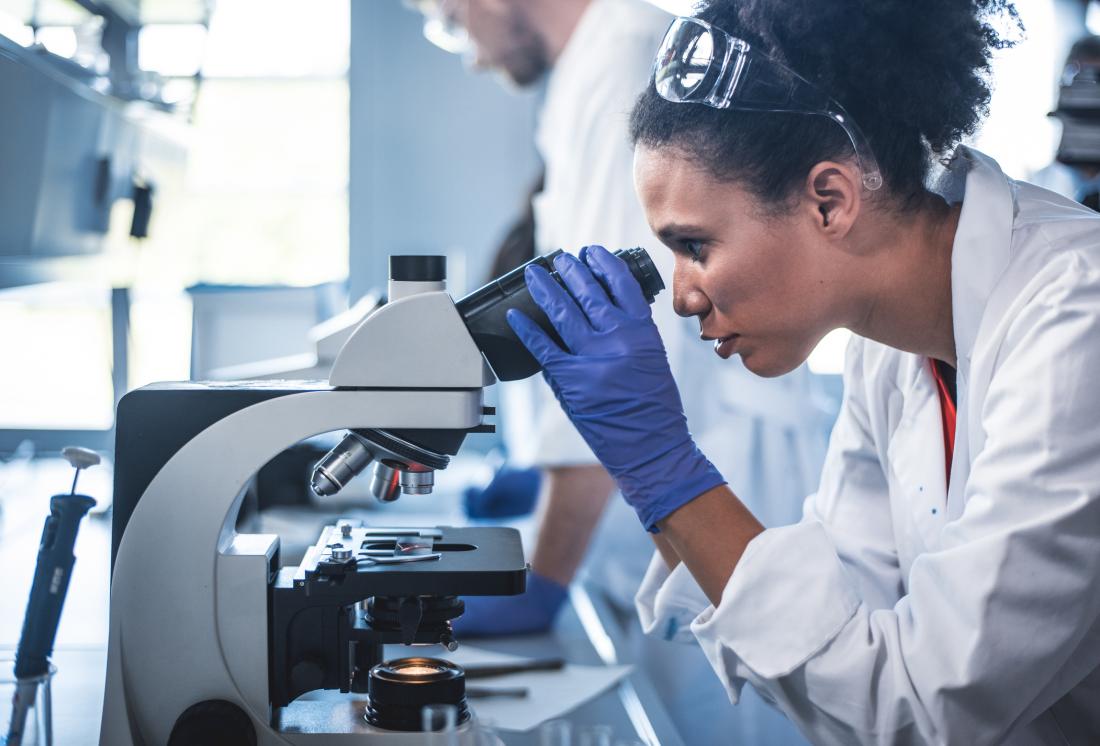 researcher looking through microscope