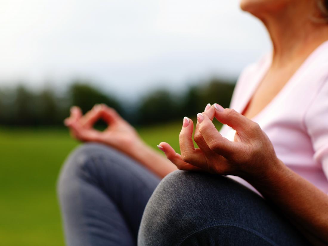 Hands of mature woman practicing yoga