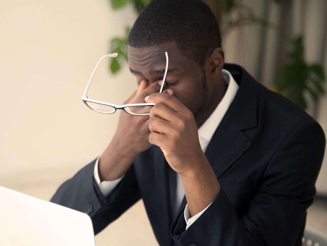 a man experiencing a headache behind the eyes because of staring at a screen for too long. 