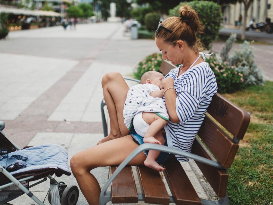 a woman breastfeeding in the street. 