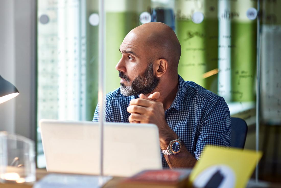 a man in an office who is distracted because of ruminating thoughts