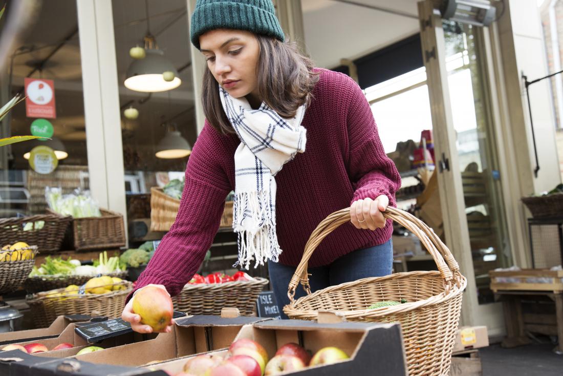 a woman reducing food waste by only buying the apples she plans to eat.