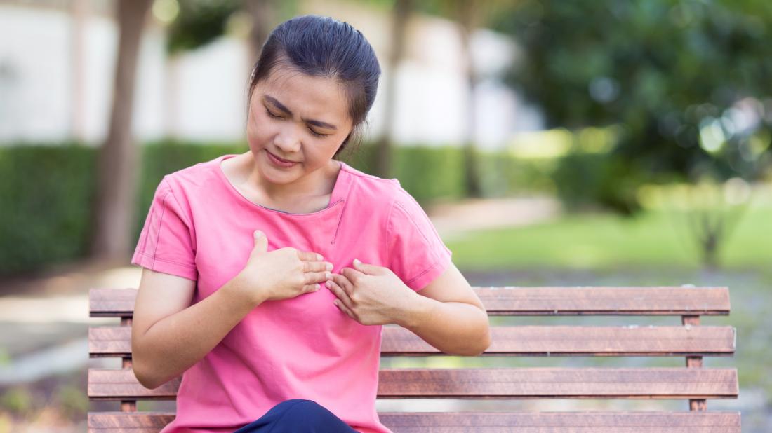 a woman sat on a bench and experiencing chest pain on left side