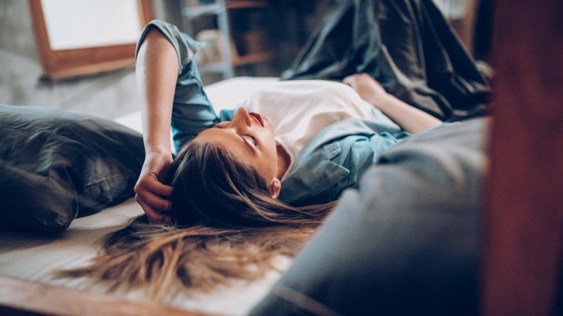 a woman lying on a bed looking irritated because she is experiencing PMS depression